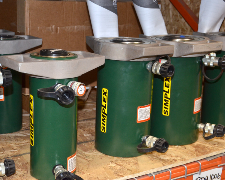 Workers monitor aluminum beams with featherlite labels moving on an industrial assembly line in a manufacturing facility.