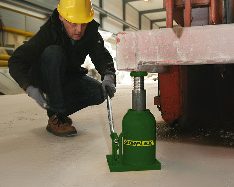 A construction worker wearing a hard hat, safety vest, and tool belt stands confidently next to a yellow featherlite ladder in a bright indoor setting.