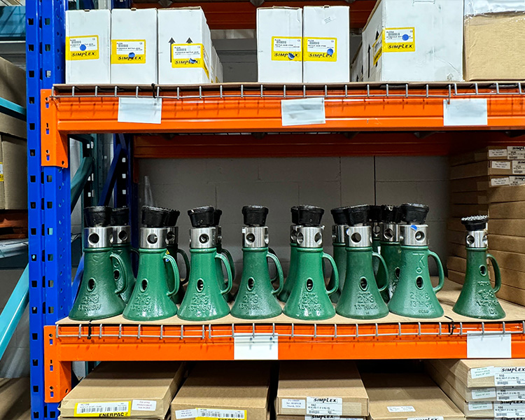 Two step ladders facing opposite directions in a large warehouse filled with rows of shelving units stocked with various boxes.