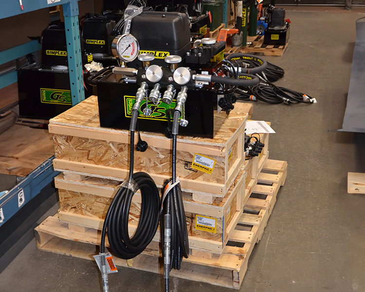 Two step ladders facing opposite directions in a large warehouse filled with rows of shelving units stocked with various boxes.